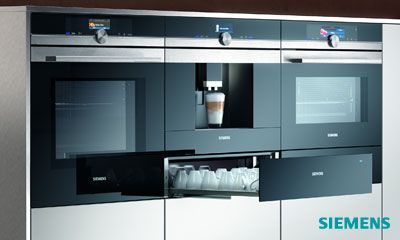 Siemens glassdraftAir Dunstabzug hinter Kochfeld mit aufsteigendem Dampf, moderne offene Küche, Frau im Hintergrund.